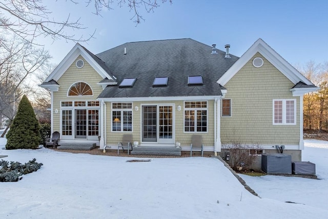 snow covered property with entry steps and roof with shingles