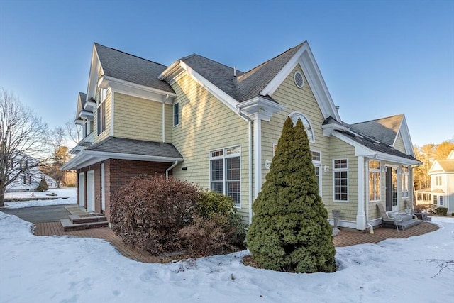 view of snowy exterior with roof with shingles