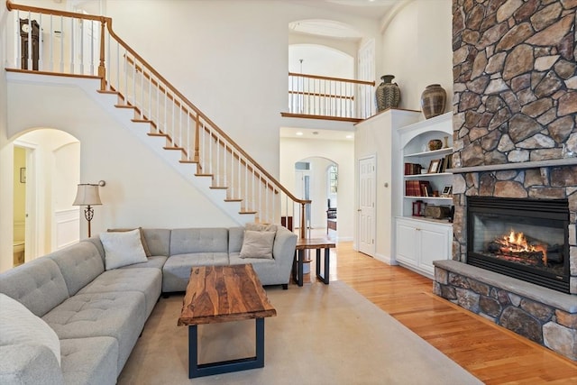 living area with baseboards, arched walkways, stairway, wood finished floors, and a fireplace