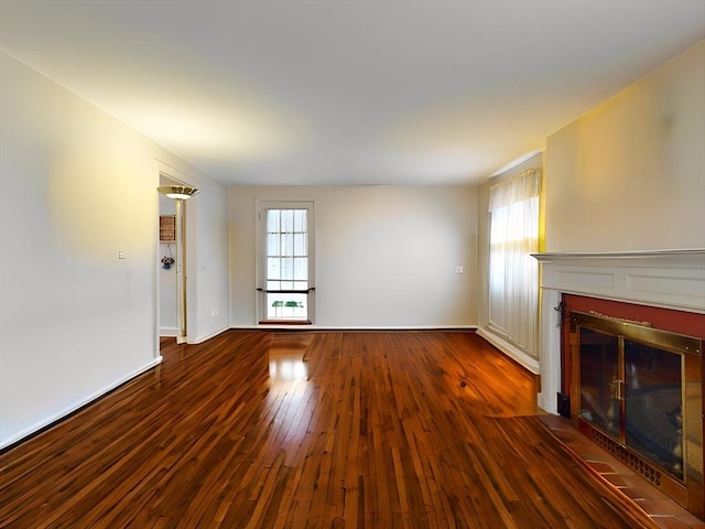 unfurnished living room featuring a fireplace with flush hearth, baseboards, and hardwood / wood-style flooring