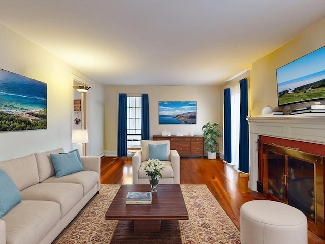 living area featuring a fireplace with flush hearth and wood finished floors