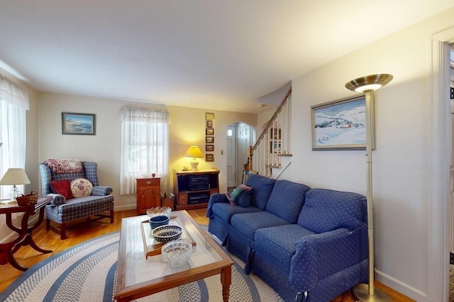 living room featuring arched walkways, stairway, baseboards, and wood finished floors