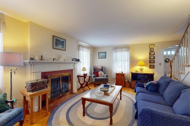 living area featuring a brick fireplace, wood finished floors, and stairs