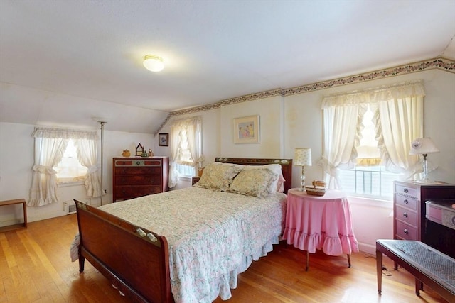 bedroom with light wood-type flooring and lofted ceiling