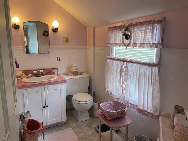 bathroom featuring lofted ceiling, wainscoting, vanity, and toilet