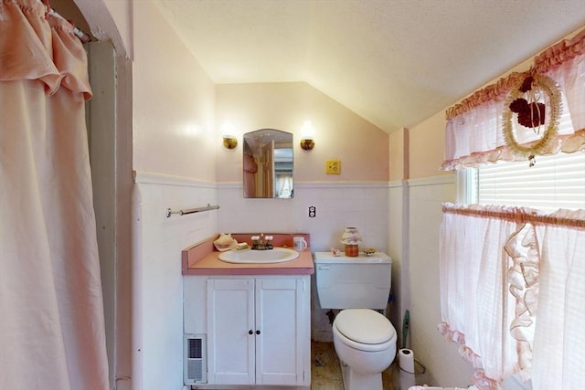 bathroom featuring vaulted ceiling, a wainscoted wall, vanity, and toilet