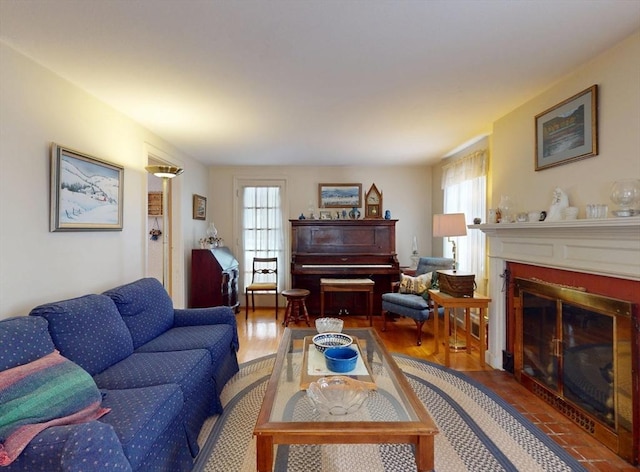 living area with wood finished floors, a fireplace with flush hearth, and a healthy amount of sunlight