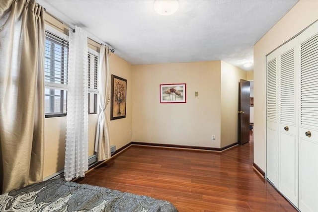 unfurnished bedroom with wood finished floors, a closet, and baseboards