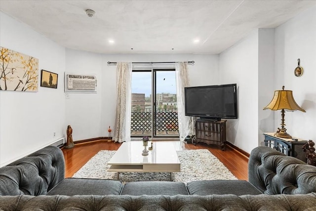 living room featuring wood finished floors, baseboards, a wall unit AC, and recessed lighting