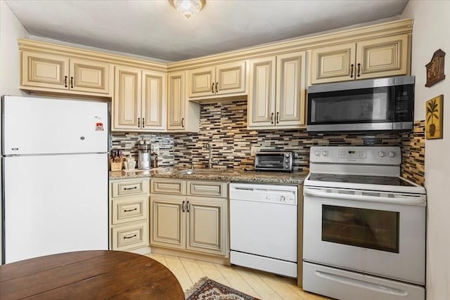 kitchen with white appliances, cream cabinets, and a sink
