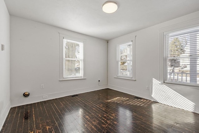 spare room featuring a wealth of natural light and dark hardwood / wood-style floors