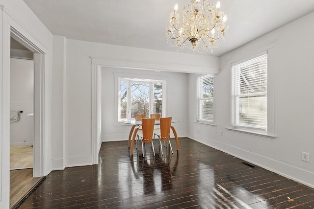 dining room with dark wood-type flooring and a chandelier