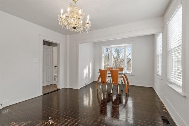 unfurnished dining area with dark hardwood / wood-style flooring and a chandelier