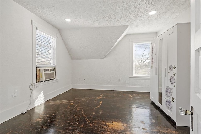 additional living space featuring lofted ceiling, dark hardwood / wood-style floors, cooling unit, and a textured ceiling