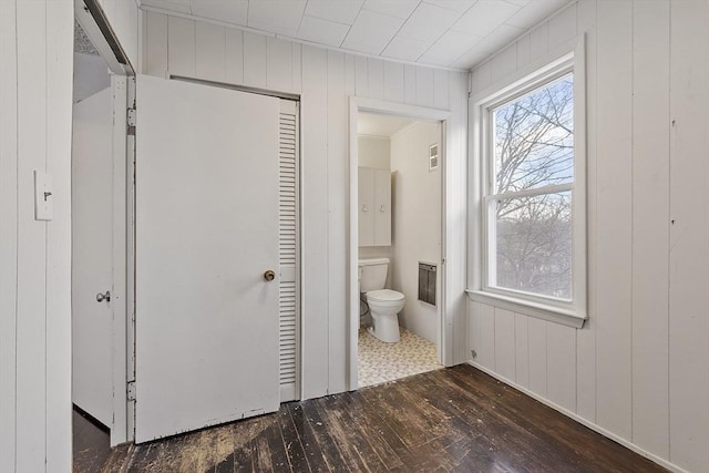 bathroom with wood-type flooring, toilet, and wood walls