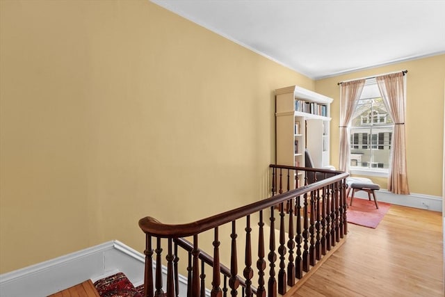 stairway with ornamental molding and wood finished floors