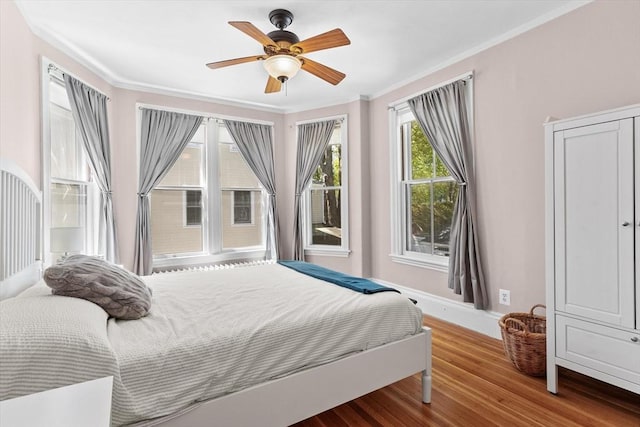 bedroom featuring baseboards, ornamental molding, ceiling fan, and wood finished floors