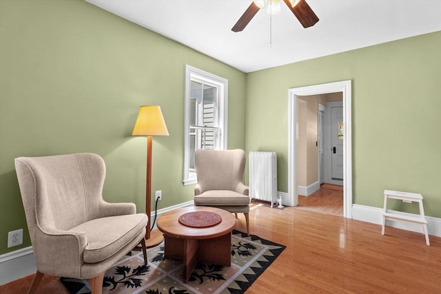 living area with ceiling fan, radiator, baseboards, and wood finished floors