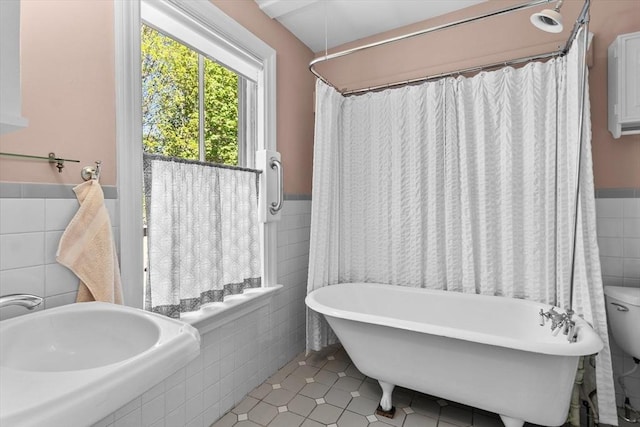 full bathroom featuring wainscoting, a freestanding bath, tile walls, and tile patterned floors