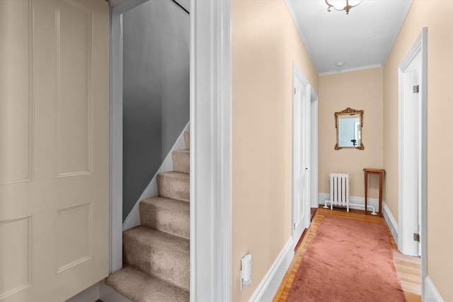 stairs with ornamental molding, wood finished floors, baseboards, and radiator heating unit