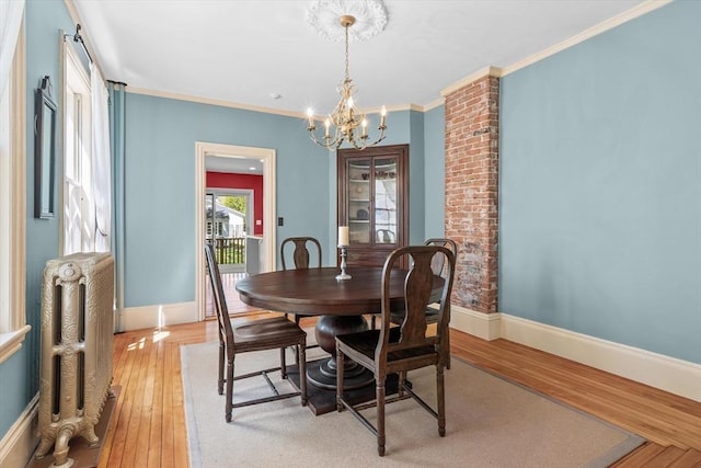 dining room featuring baseboards, radiator, a chandelier, and light wood-style flooring
