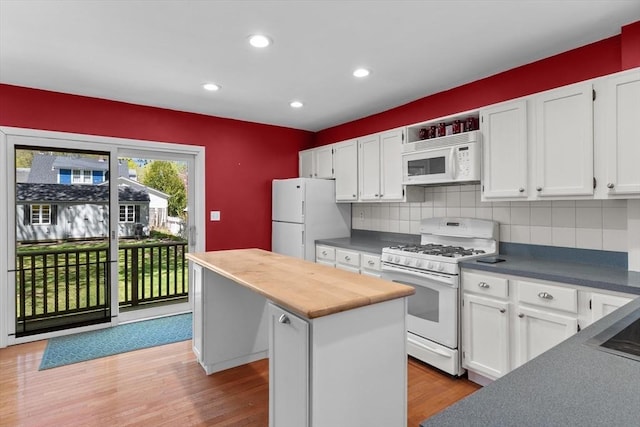 kitchen featuring white appliances, backsplash, white cabinets, a kitchen island, and light wood-style floors