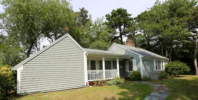 view of front of house with covered porch, a front lawn, and cooling unit