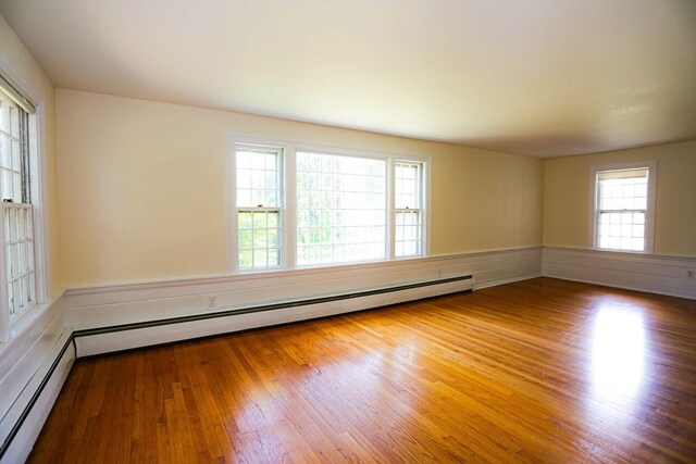 unfurnished bedroom featuring a baseboard heating unit and wood-type flooring