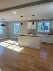 kitchen with beamed ceiling, pendant lighting, and white cabinetry