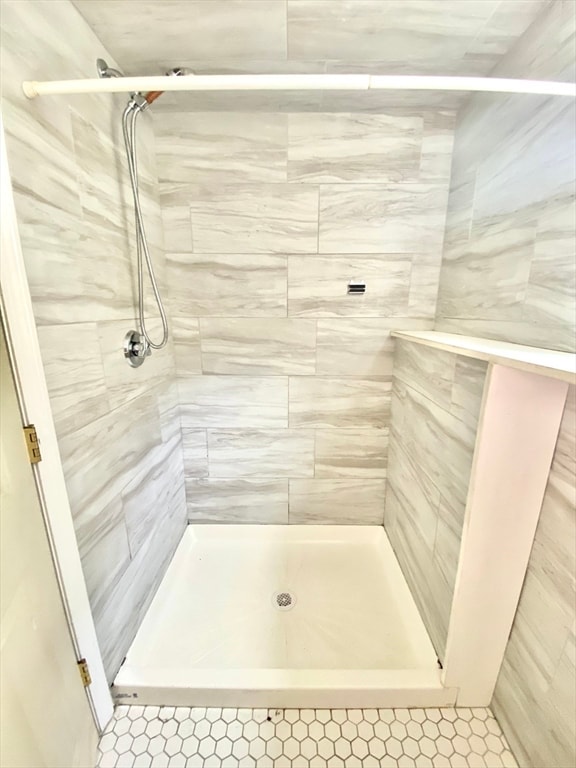 bathroom featuring tiled shower and tile patterned flooring