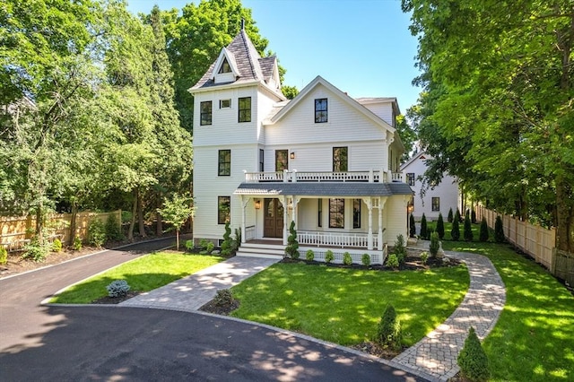 victorian-style house featuring a porch and a front lawn