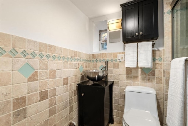 bathroom featuring vanity, a shower, tile walls, and toilet