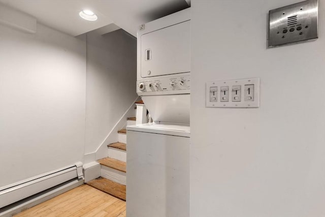 stairway with baseboard heating, stacked washer / dryer, and hardwood / wood-style floors