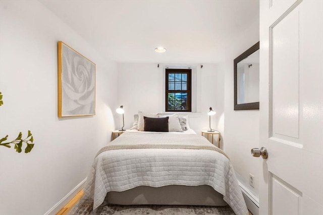 bedroom with hardwood / wood-style flooring and baseboard heating