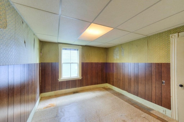 empty room featuring wallpapered walls, a wainscoted wall, wooden walls, and baseboards