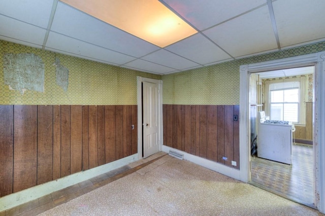 spare room featuring a wainscoted wall, wooden walls, wallpapered walls, and a paneled ceiling