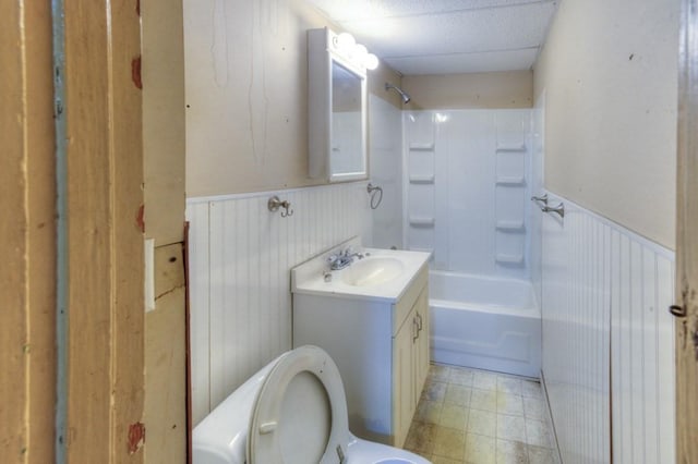 full bath featuring a wainscoted wall, vanity, bathtub / shower combination, and toilet