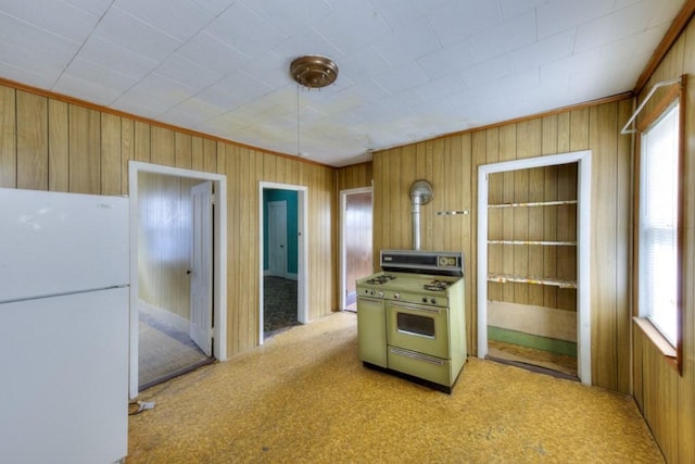 kitchen featuring freestanding refrigerator, double oven range, wooden walls, and carpet
