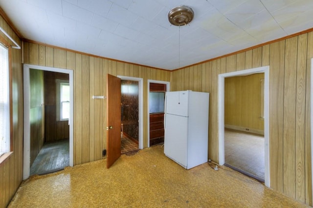 kitchen featuring freestanding refrigerator, wood walls, and crown molding