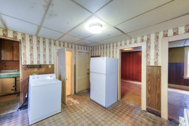 kitchen with freestanding refrigerator, washer / dryer, wallpapered walls, tile patterned floors, and wainscoting