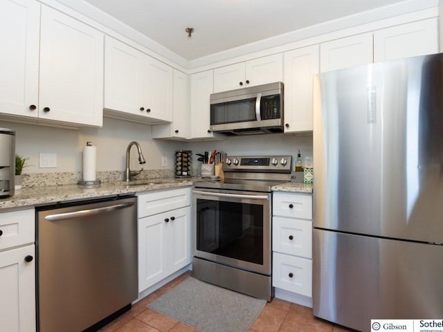 kitchen featuring white cabinets, appliances with stainless steel finishes, light tile patterned floors, and sink