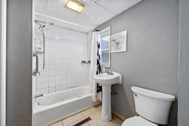 full bathroom with a drop ceiling, tile patterned floors, sink, toilet, and shower / bathtub combination with curtain