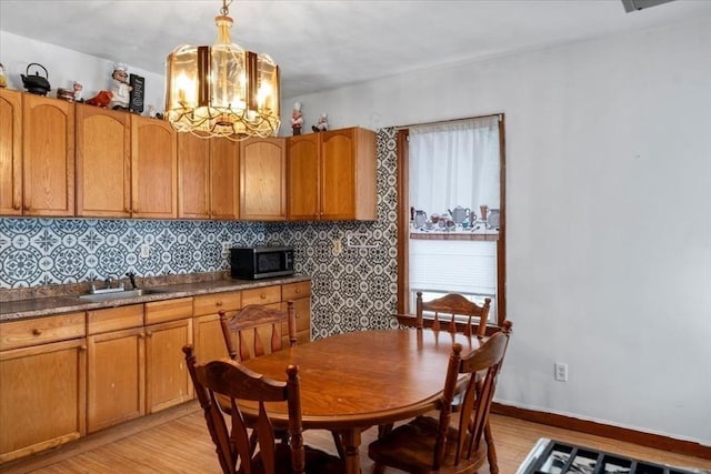 dining space with light wood-type flooring, a notable chandelier, and sink