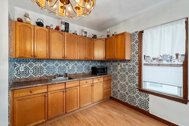 kitchen with light hardwood / wood-style floors, an inviting chandelier, a wealth of natural light, and sink