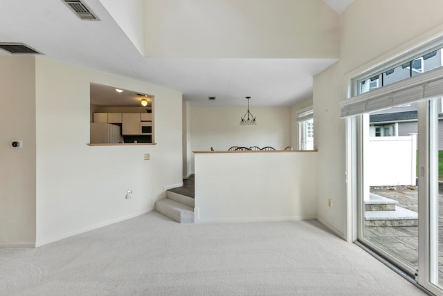 empty room with an inviting chandelier and carpet flooring