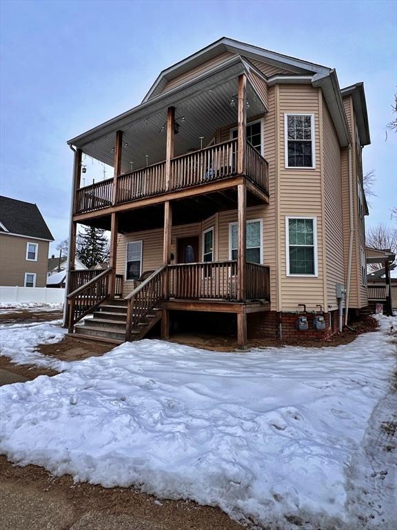 snow covered rear of property with a balcony