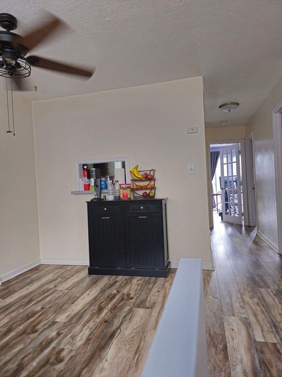 bar with a textured ceiling, wood finished floors, a ceiling fan, and baseboards