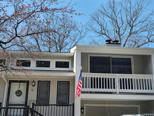 view of front of home featuring a chimney, a balcony, and an attached garage