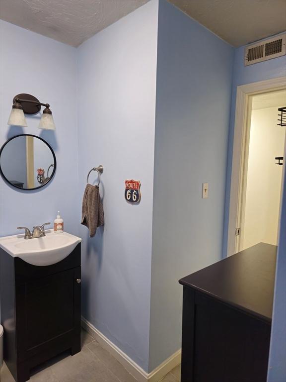bathroom featuring tile patterned flooring, visible vents, vanity, and baseboards