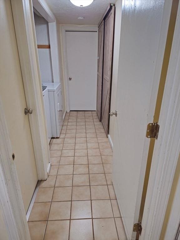 corridor with light tile patterned floors and washer and dryer
